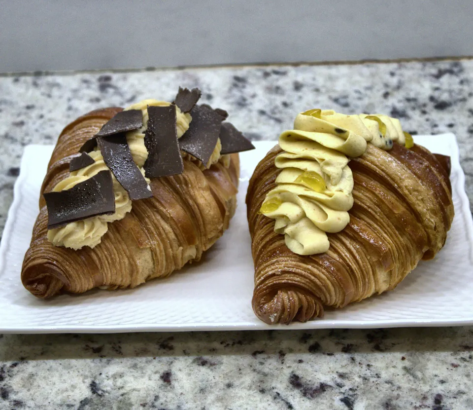 Dos croissants rellenos de crema sobre un plato blanco
