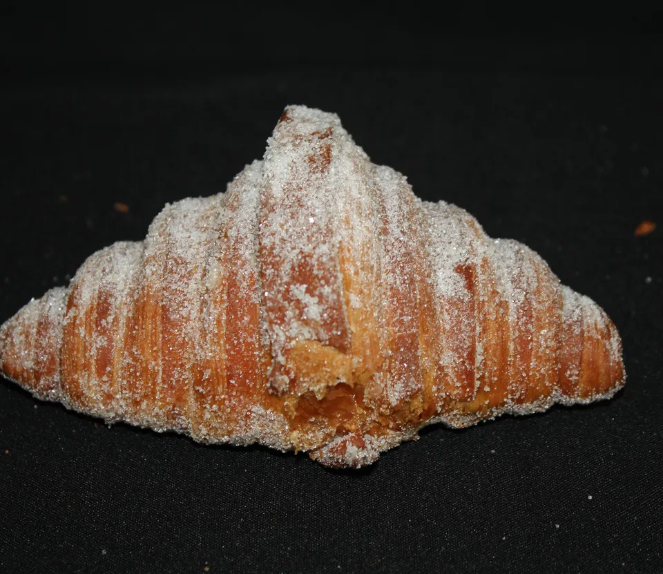 Croissant Pixán cubierto de azúcar, sobre fondo negro